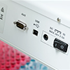 Close-up of electronic device ports, including a serial port, USB port, DC power input, and power switch—often found on autosamplers—with blurred lab equipment in the background.